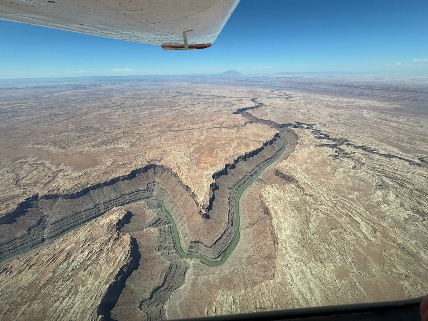 View from under a high wing over a deep, winding desert canyon
