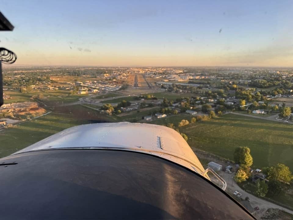Engine cowling over a town and runway at dusk